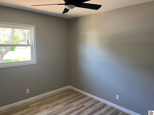 unfurnished room featuring baseboards, ceiling fan, light wood-style floors, and a textured ceiling