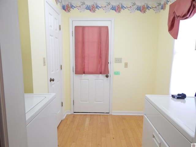 laundry area featuring separate washer and dryer, light wood-style flooring, laundry area, and baseboards