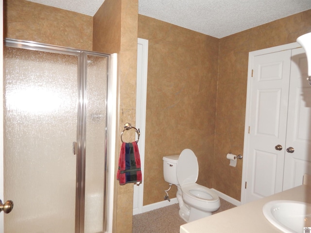 bathroom with a shower stall, vanity, toilet, baseboards, and a textured ceiling