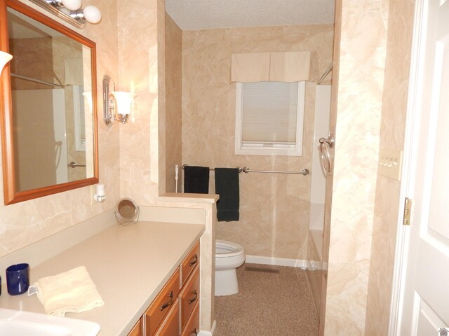 bathroom with toilet, walk in shower, vanity, and tile walls