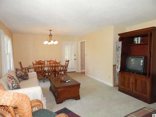 living room with an inviting chandelier, baseboards, and light carpet