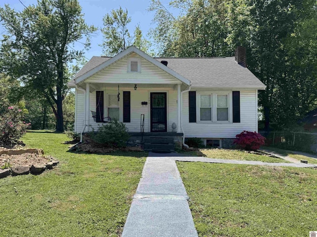 bungalow featuring a porch, a front lawn, a shingled roof, and a chimney