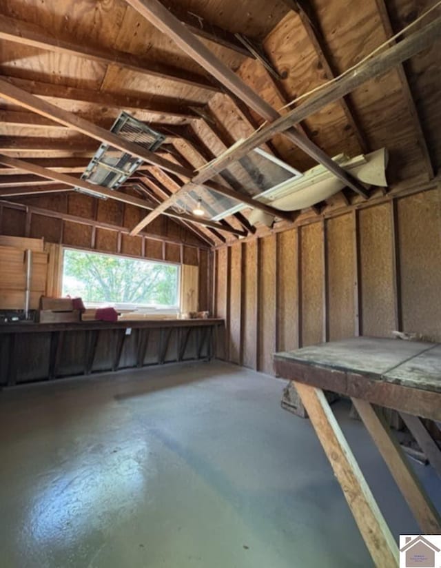 miscellaneous room with concrete floors, a garage, and lofted ceiling