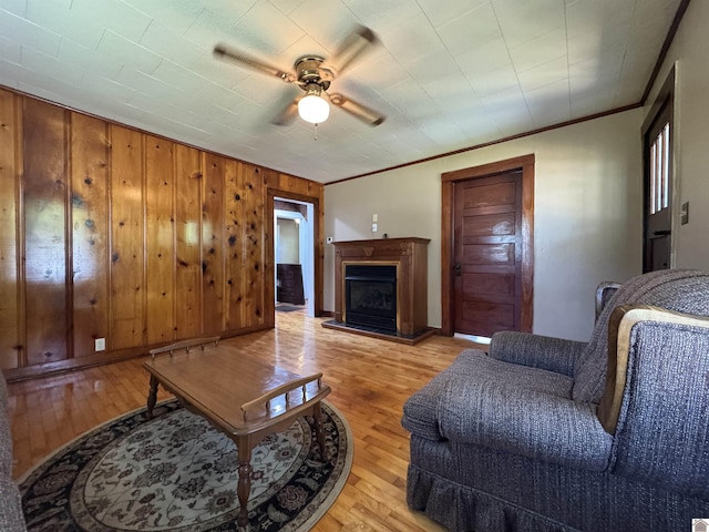 living area with ceiling fan, light wood-style floors, crown molding, and a fireplace with raised hearth