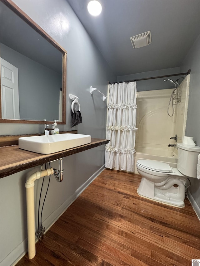 full bathroom featuring wood finished floors, shower / bath combo with shower curtain, toilet, a sink, and visible vents