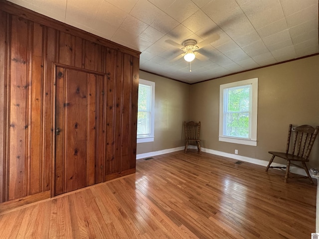 spare room featuring crown molding, a ceiling fan, baseboards, and light wood-style floors