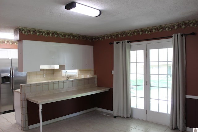 1725 Evelyn Dr, Paducah, KY 42003 - kitchen featuring stainless steel fridge with ice dispenser, white cabinets, a textured ceiling, backsplash, and light tile patterned floors