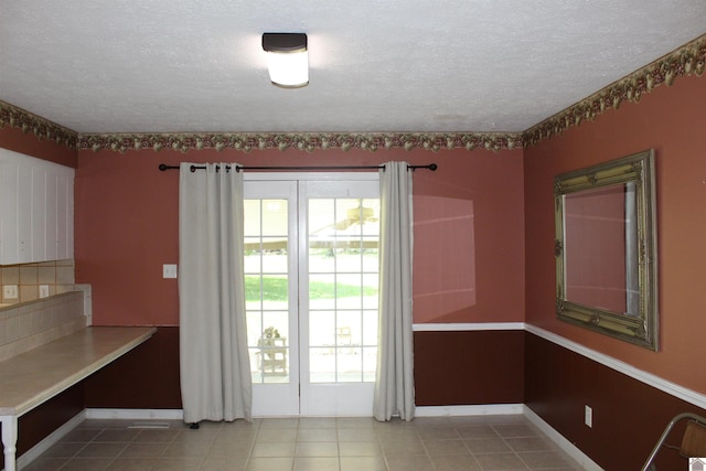 1725 Evelyn Dr, Paducah, KY 42003 - unfurnished dining area featuring a textured ceiling, tile patterned floors, and baseboards