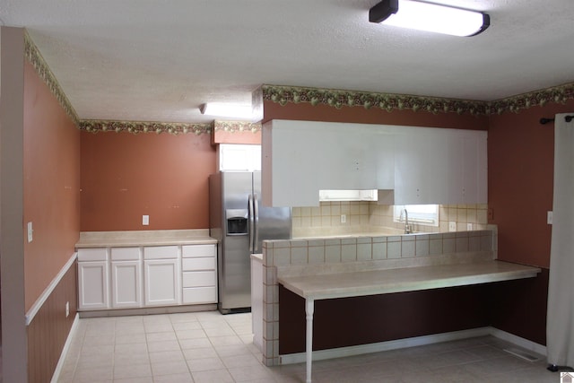 1725 Evelyn Dr, Paducah, KY 42003 - kitchen with stainless steel refrigerator with ice dispenser, white cabinetry, tasteful backsplash, a textured ceiling, and light tile patterned floors