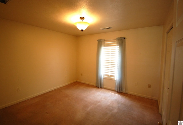 empty room with carpet floors, baseboards, and visible vents