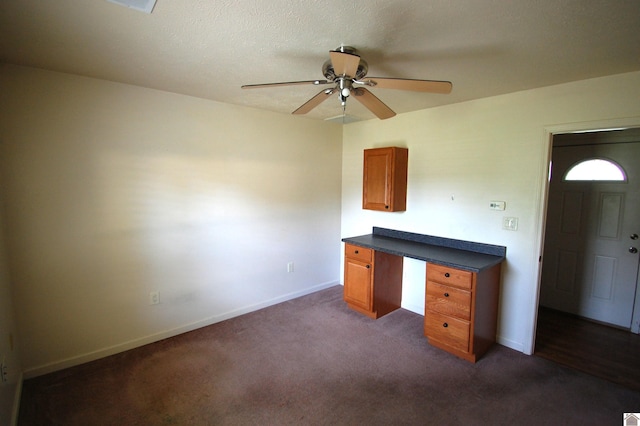 unfurnished office featuring baseboards, a ceiling fan, and dark carpet