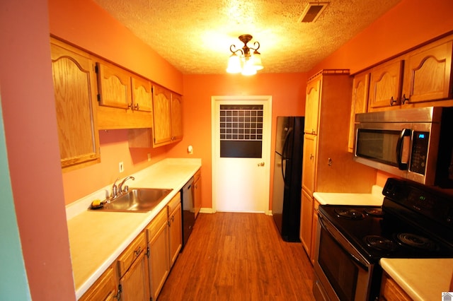 kitchen with a sink, a textured ceiling, electric stove, freestanding refrigerator, and stainless steel microwave