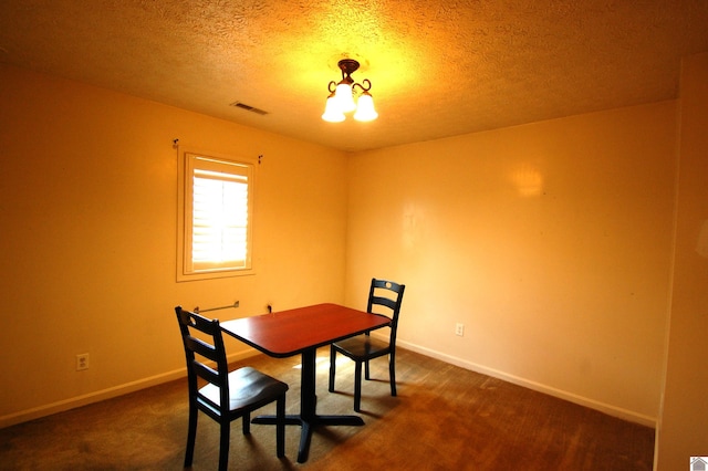 dining space with visible vents, a textured ceiling, baseboards, and dark colored carpet
