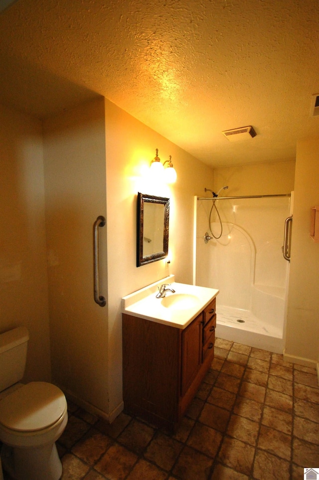 full bath featuring visible vents, vanity, toilet, a textured ceiling, and a stall shower