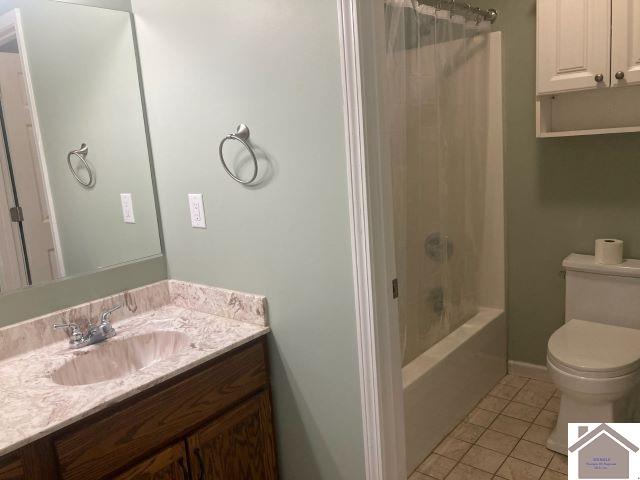 full bath featuring tile patterned flooring, toilet, vanity, shower / bath combination with curtain, and baseboards