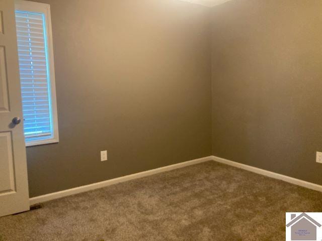 empty room featuring carpet and baseboards