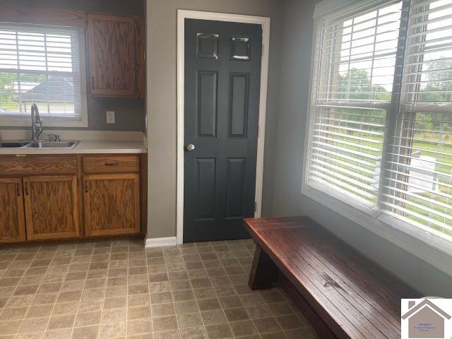 kitchen with a sink, brown cabinets, light countertops, and baseboards
