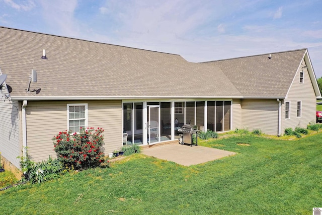 rear view of property featuring a lawn, a patio, a sunroom, and roof with shingles