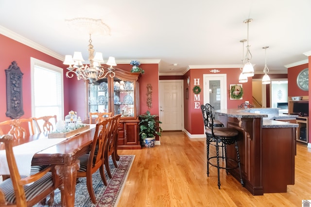 dining area with crown molding, light wood-style floors, and a notable chandelier
