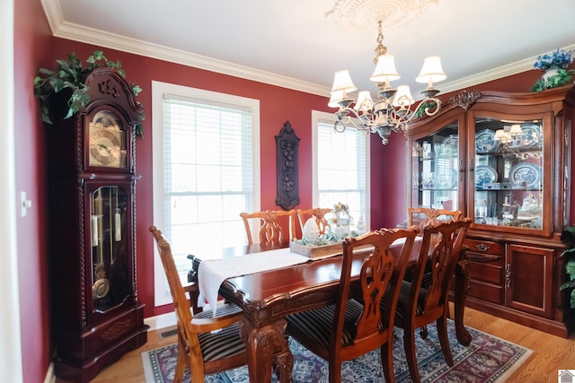 dining area with an inviting chandelier, ornamental molding, and light wood finished floors