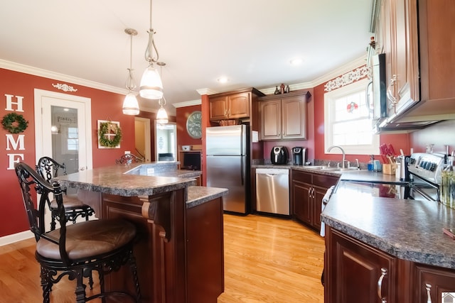 kitchen with dark countertops, appliances with stainless steel finishes, crown molding, and a kitchen bar