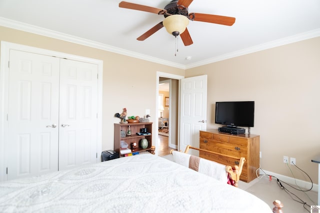 bedroom with ceiling fan, ornamental molding, baseboards, and a closet