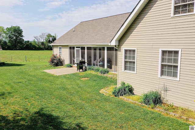 rear view of house with fence, a shingled roof, a sunroom, a patio area, and a lawn