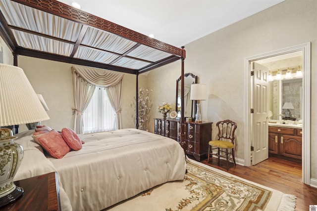 bedroom featuring ensuite bathroom, baseboards, and wood finished floors
