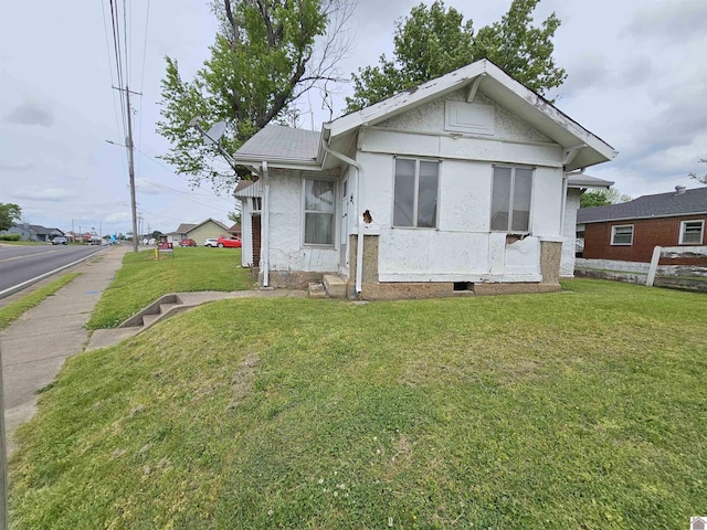 bungalow-style house with a front lawn, stucco siding, and fence