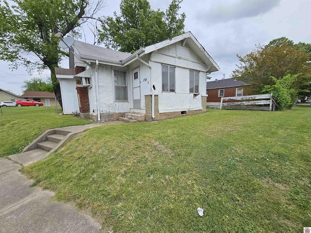 view of front facade with stucco siding, fence, and a front lawn