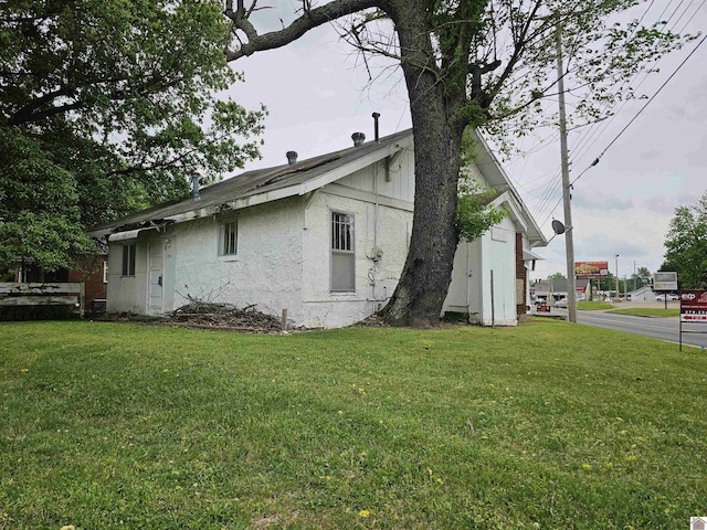 view of side of property featuring a lawn and stucco siding