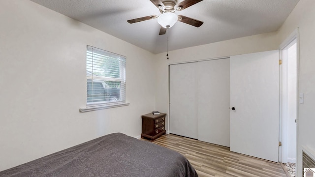 bedroom featuring a closet, a ceiling fan, light wood finished floors, and a textured ceiling