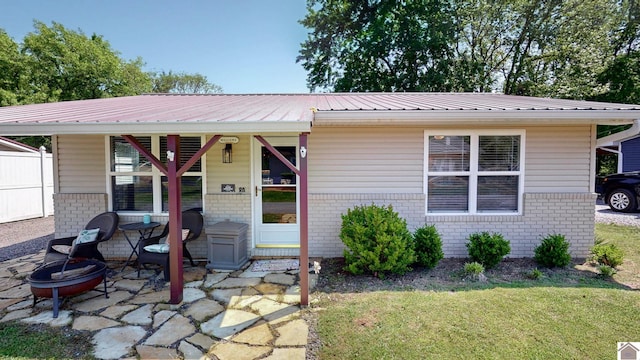 view of front of property with a front yard, a fire pit, metal roof, and brick siding