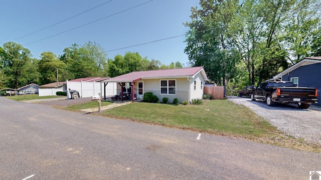 ranch-style house with fence, metal roof, driveway, and a front lawn