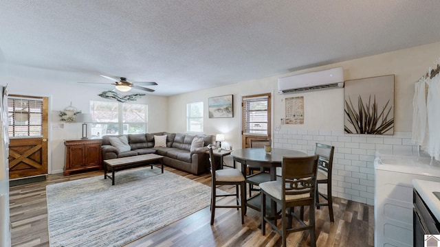 living area featuring a wall mounted air conditioner, a textured ceiling, a ceiling fan, and wood finished floors