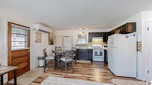 kitchen featuring light wood-type flooring, a sink, light countertops, an AC wall unit, and white appliances