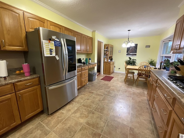 kitchen featuring dark countertops, appliances with stainless steel finishes, a chandelier, brown cabinetry, and pendant lighting