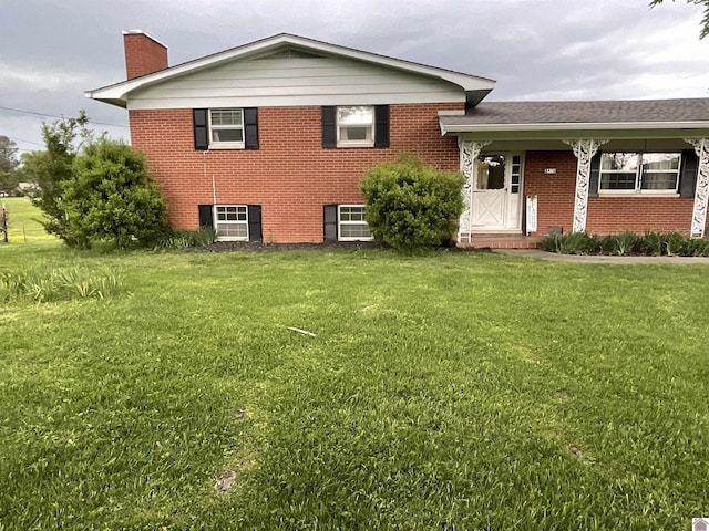 view of front of property featuring a chimney, a front yard, and brick siding
