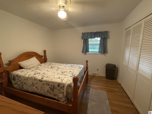 bedroom featuring baseboards, wood finished floors, and a closet