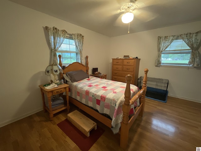 bedroom with ceiling fan, baseboards, multiple windows, and wood finished floors