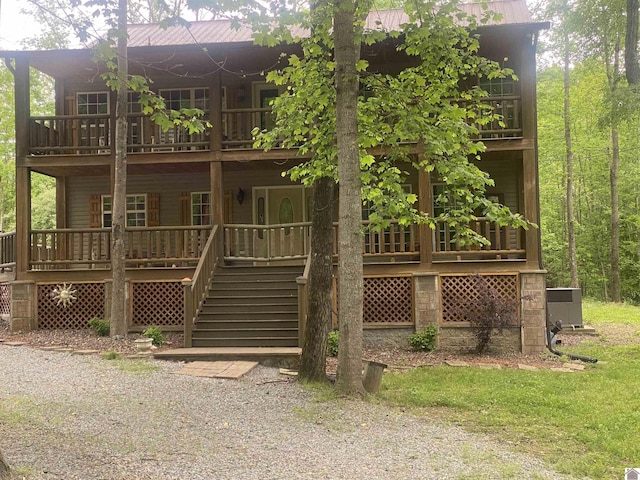 back of house with covered porch, stairway, and a balcony