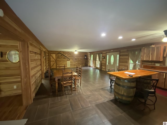 dining area featuring recessed lighting, wood walls, a ceiling fan, and stairway