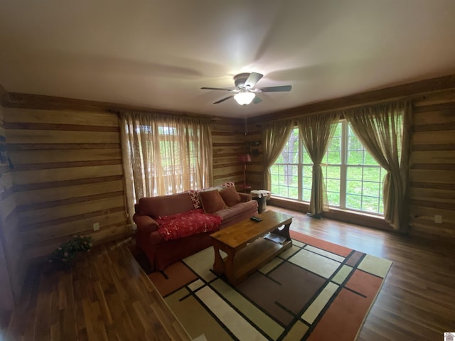 living room featuring wooden walls, ceiling fan, and wood finished floors