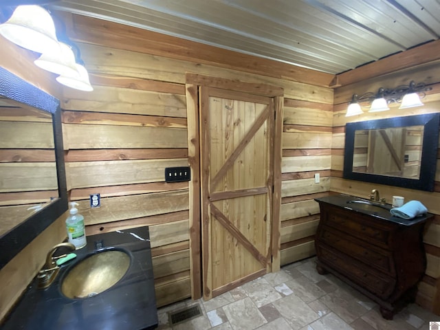 bathroom with vanity, wooden walls, and stone finish floor