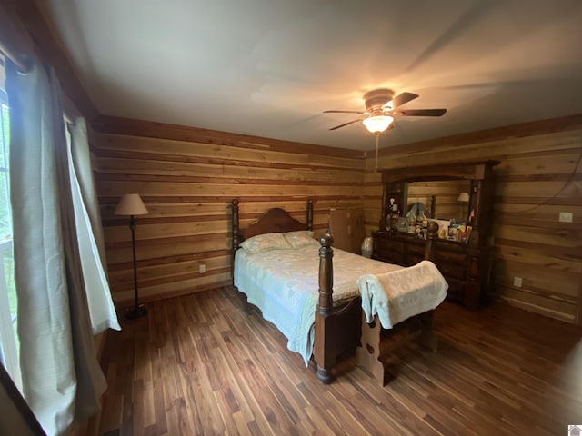 bedroom with wooden walls, ceiling fan, and wood finished floors