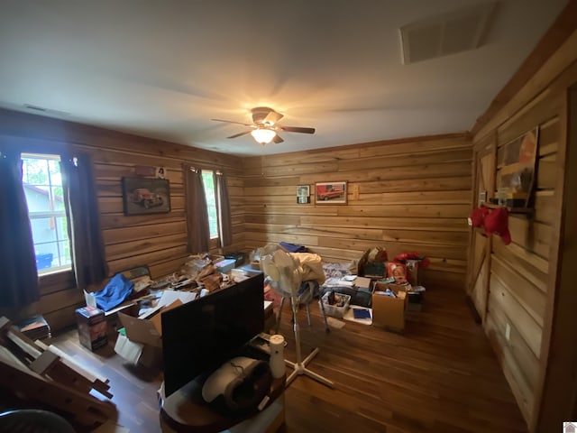 misc room with a ceiling fan, wood walls, visible vents, and wood finished floors