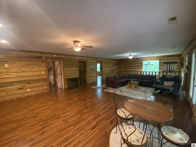 living room featuring wood walls, ceiling fan, and wood finished floors