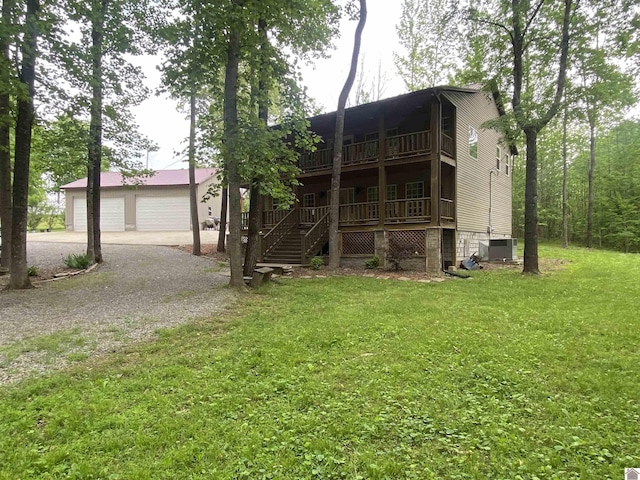 view of front of home with central AC, a garage, a front yard, covered porch, and gravel driveway