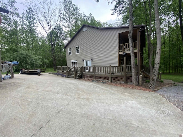 view of property exterior featuring driveway, a wooden deck, and a balcony