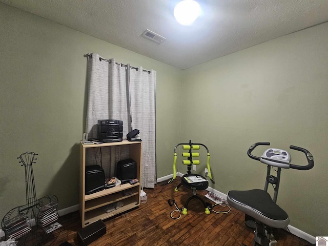 workout room featuring baseboards, visible vents, and wood finished floors